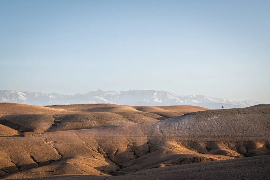 Collines du désert de pierre devant les sommets enneigés de l’Atlas