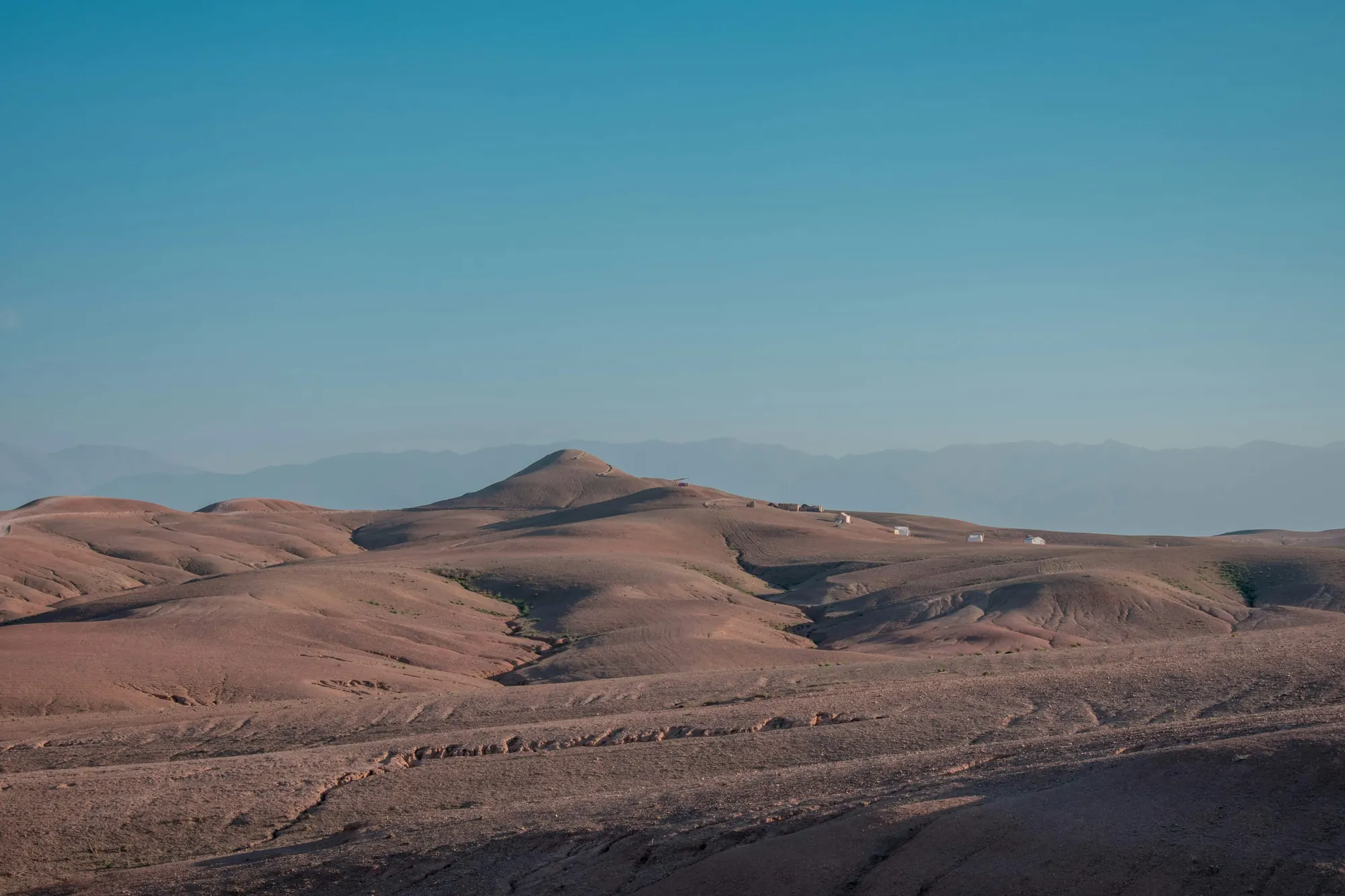 Collines minérales du désert d’Agafay avec les montagnes de l’Atlas à l’horizon