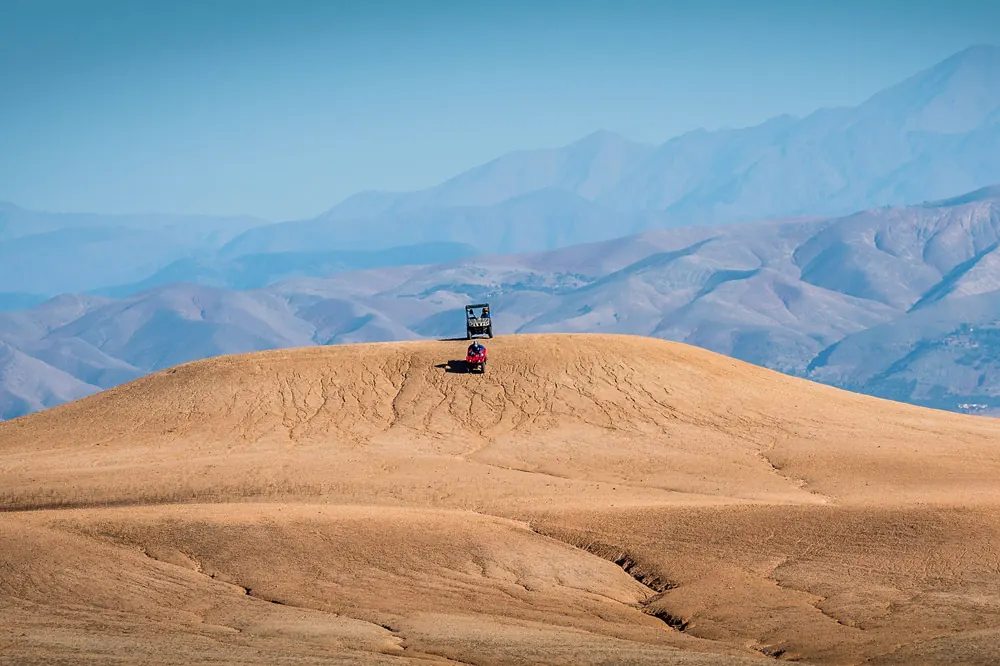 Voyageur en quad au sommet d’une colline avec les montagnes à l’horizon
