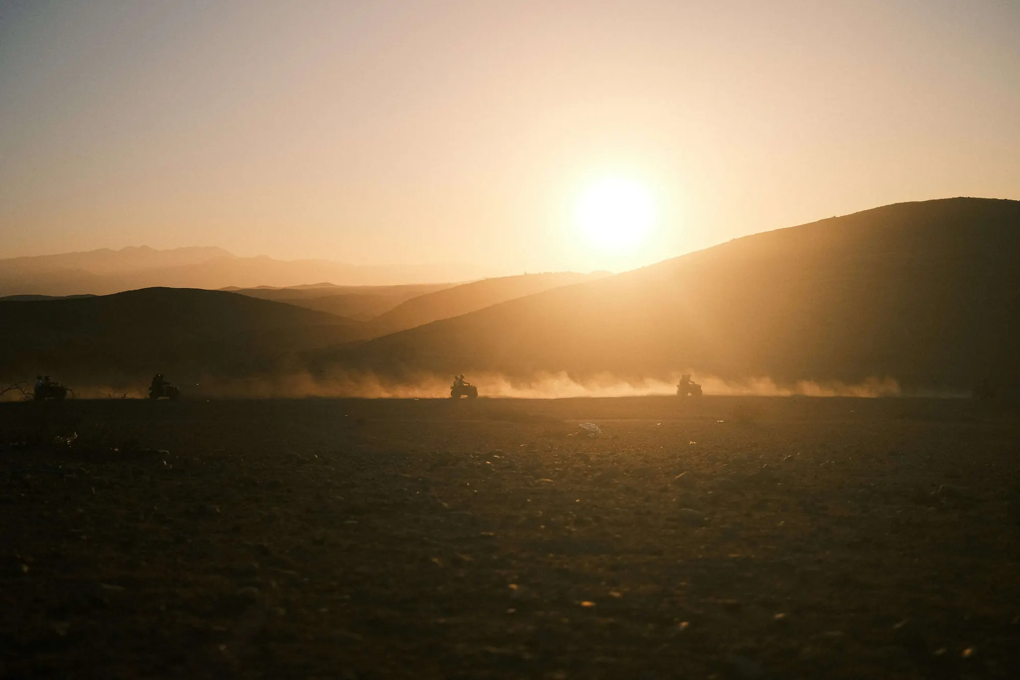 Quads sur une piste du désert d’Agafay dans la lumière dorée du coucher du soleil